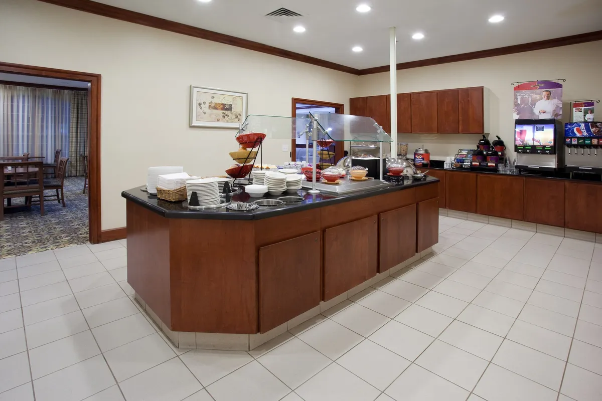 The photo features a breakfast bar setup with a display of food and a beverage station. The arrangement suggests a welcoming atmosphere for families or guests to gather, enjoy meals, and connect—mirroring the section’s focus on dining and social flexibility.