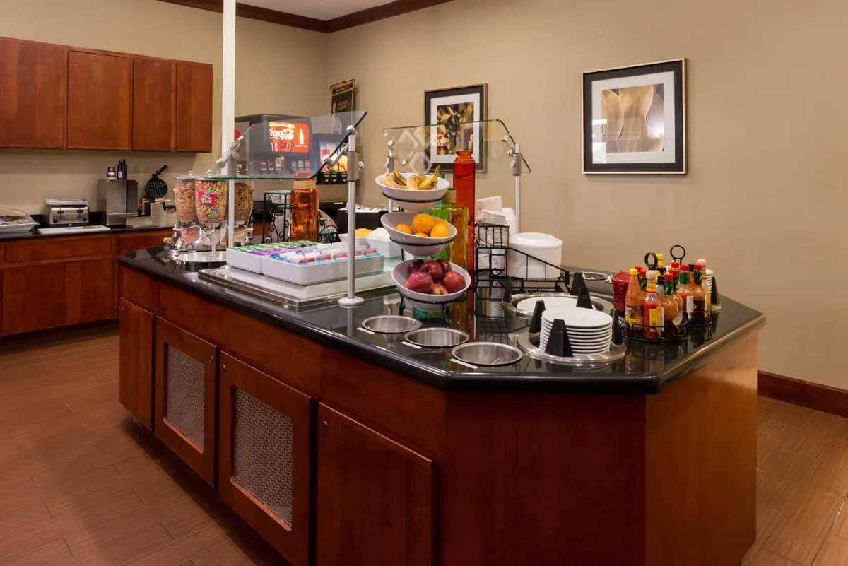 A cheerful interior breakfast bar with a fruit display, beverage options, and snack containers, inviting guests to enjoy a meal together or socialize in a comfortable, communal space.